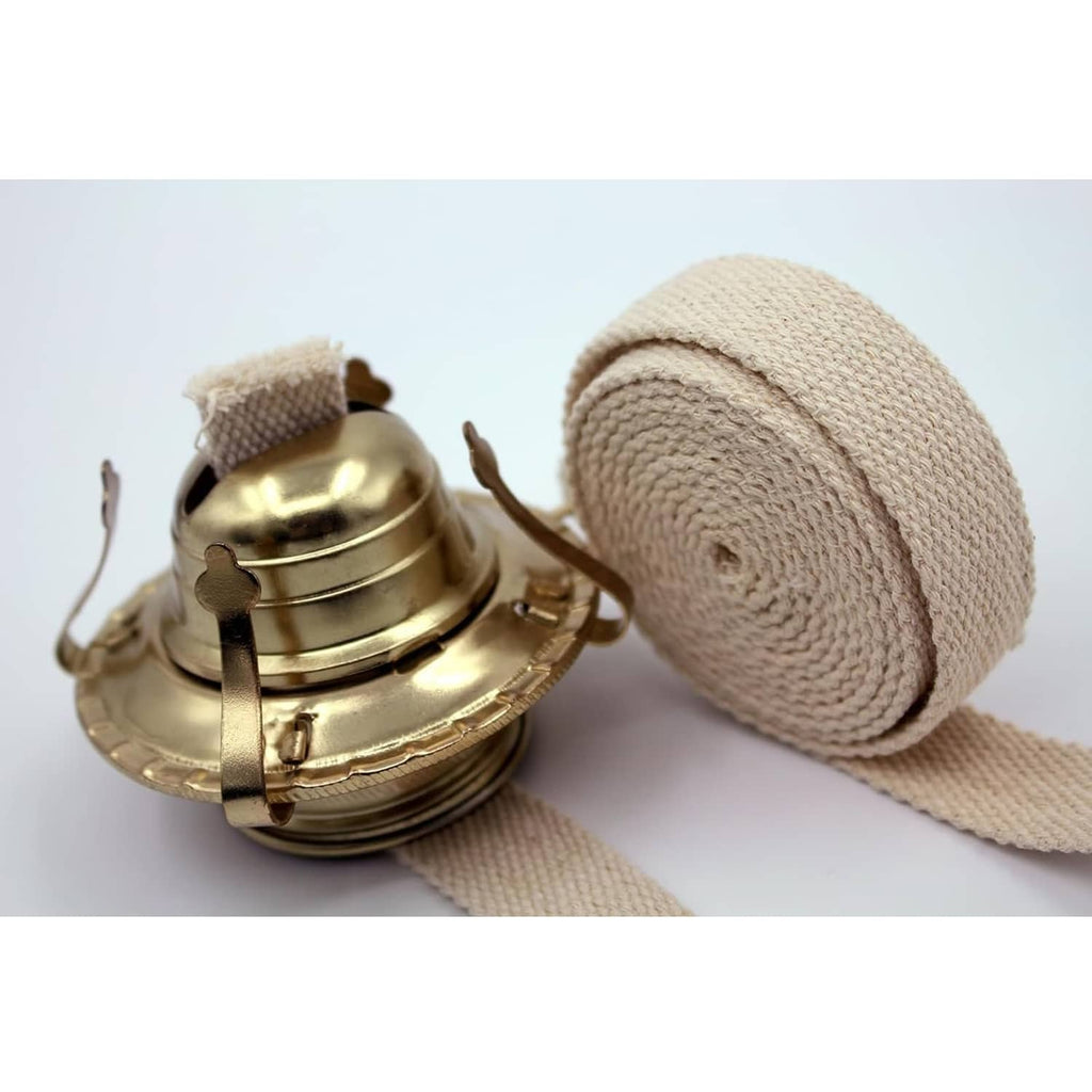 Cotton oil lamp wick roll with blue stitching beside brass oil lamp