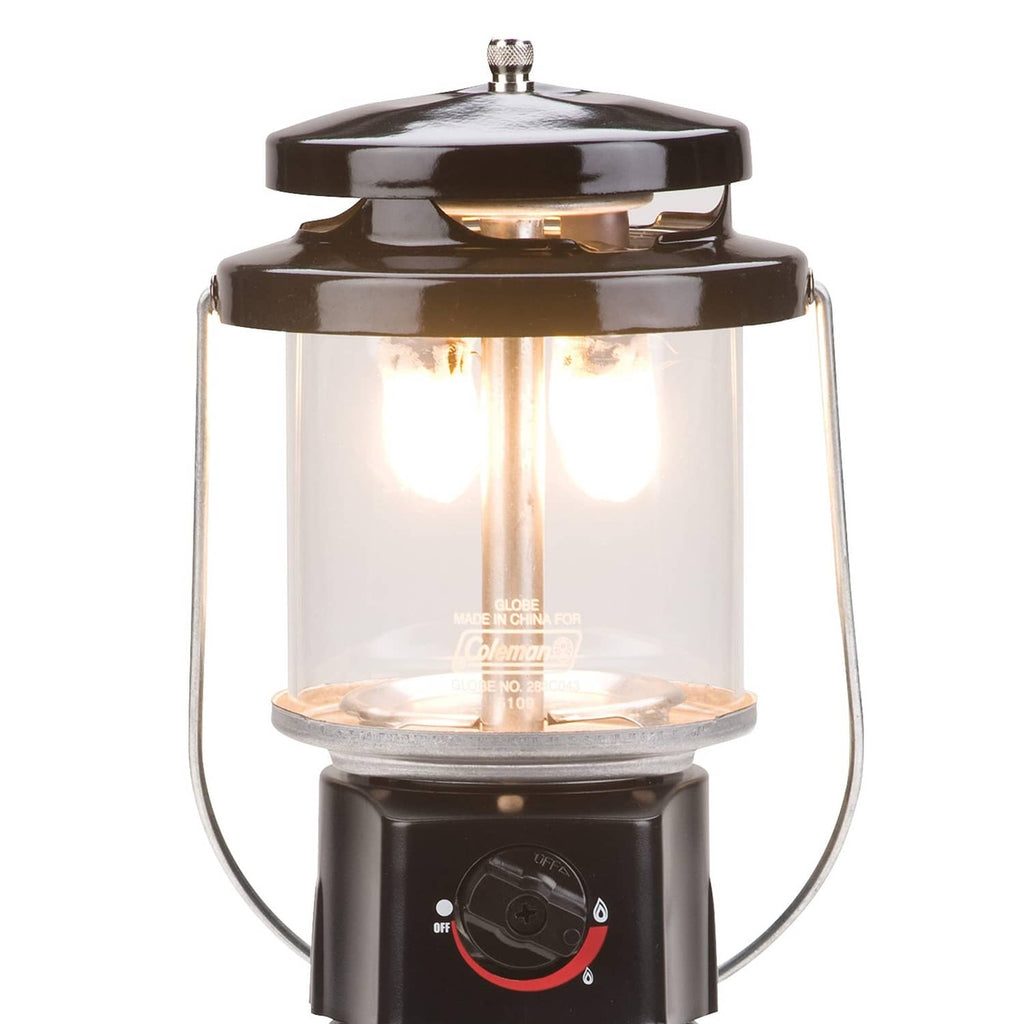 Coleman propane lantern with lit burner, clear glass housing, and metal top