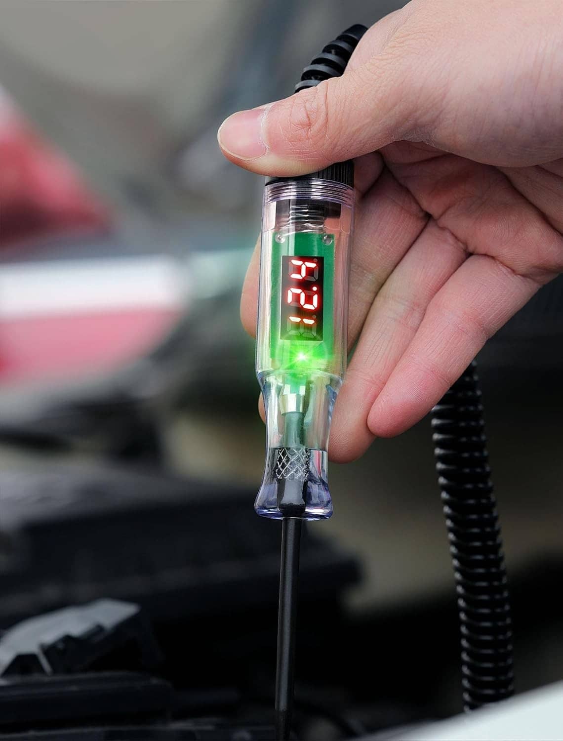 Automotive test light held by hand with green indicator and red LED voltage reading