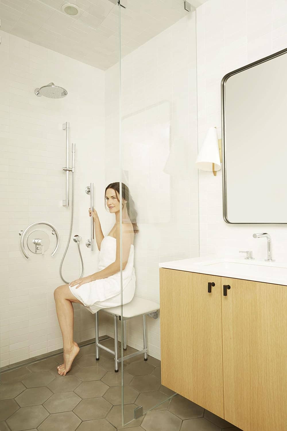 Stainless steel straight shower grab bar, mounted on glass wall.