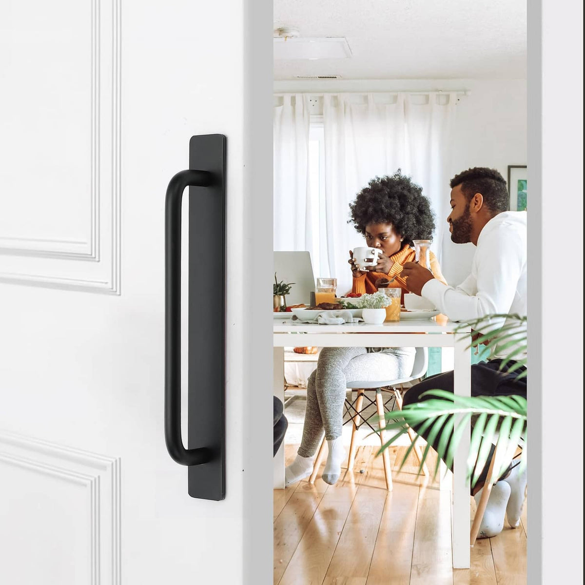 Black self-adhesive cabinet handle mounted on a white cabinet door