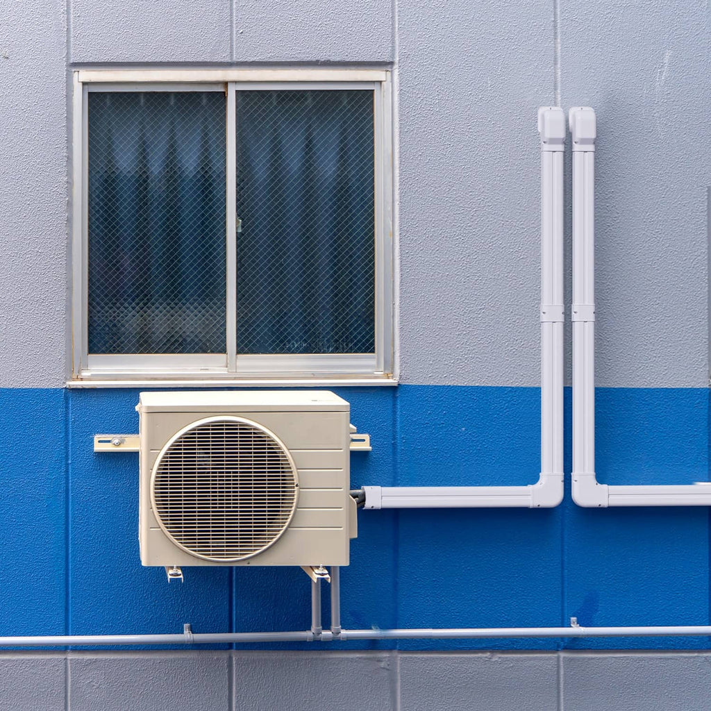 White PVC line set cover with vertical sections and L-bend connecting outdoor unit