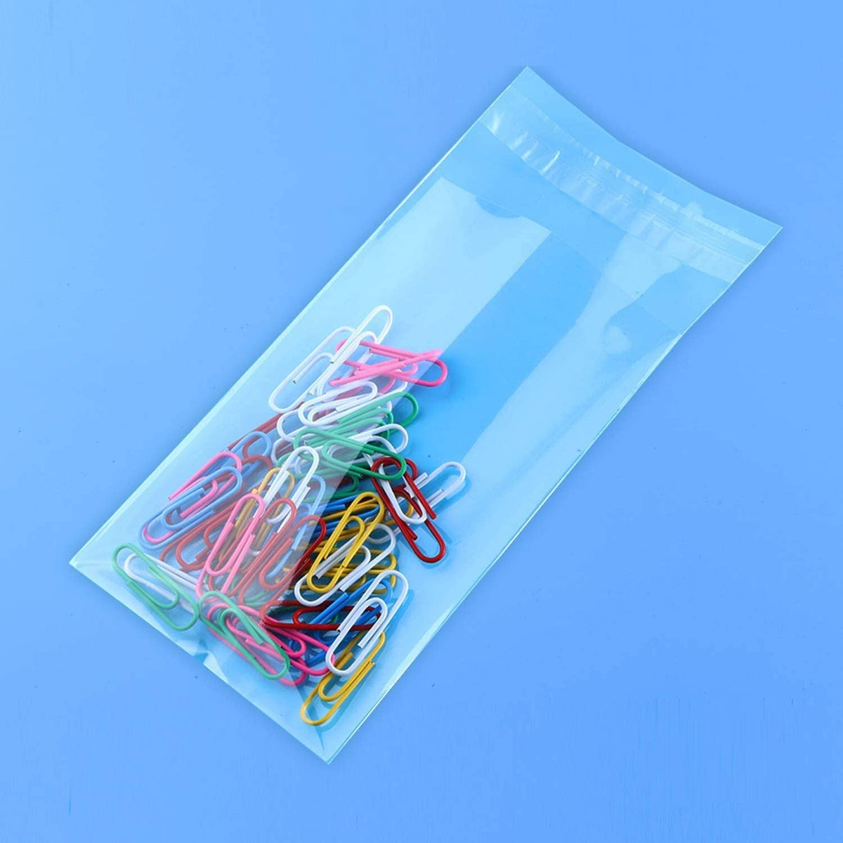 Clear self-sealing cellophane bag with mixed-color paper clips inside