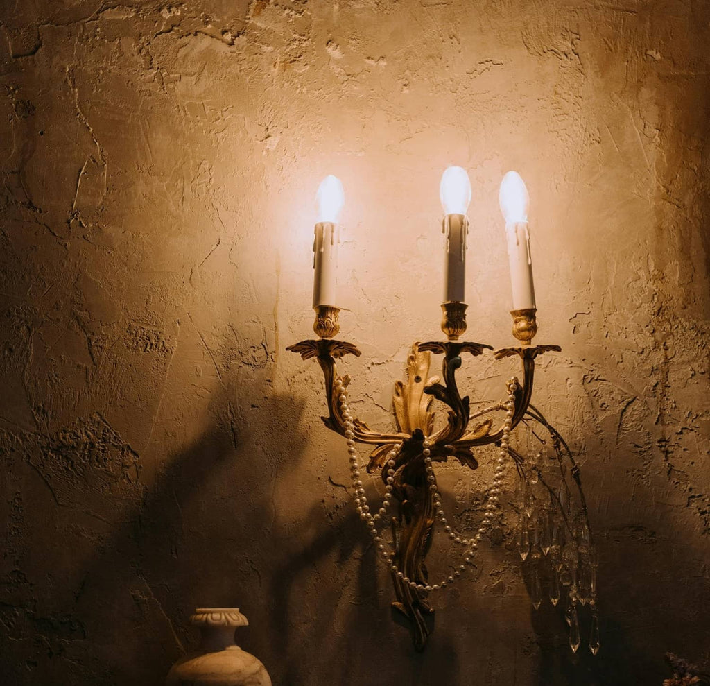 Three lit candle-style bulbs on a candelabra wall fixture