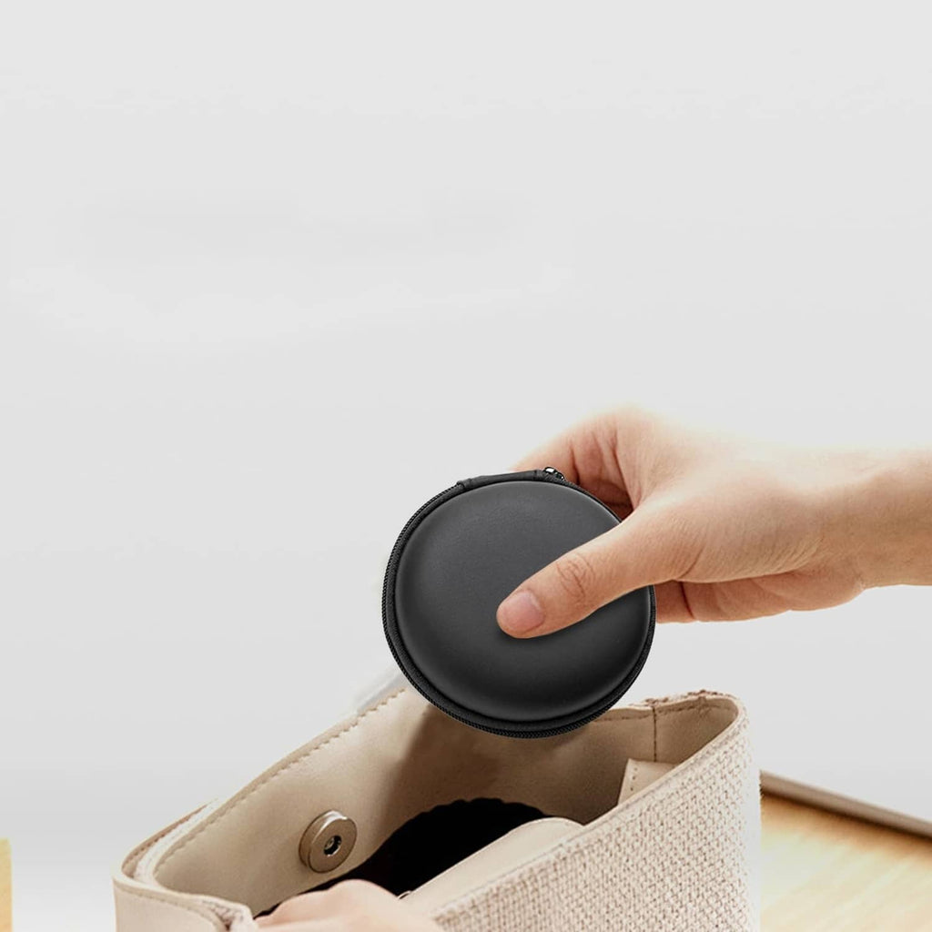 Black round earphone case being closed by a hand over the top shell