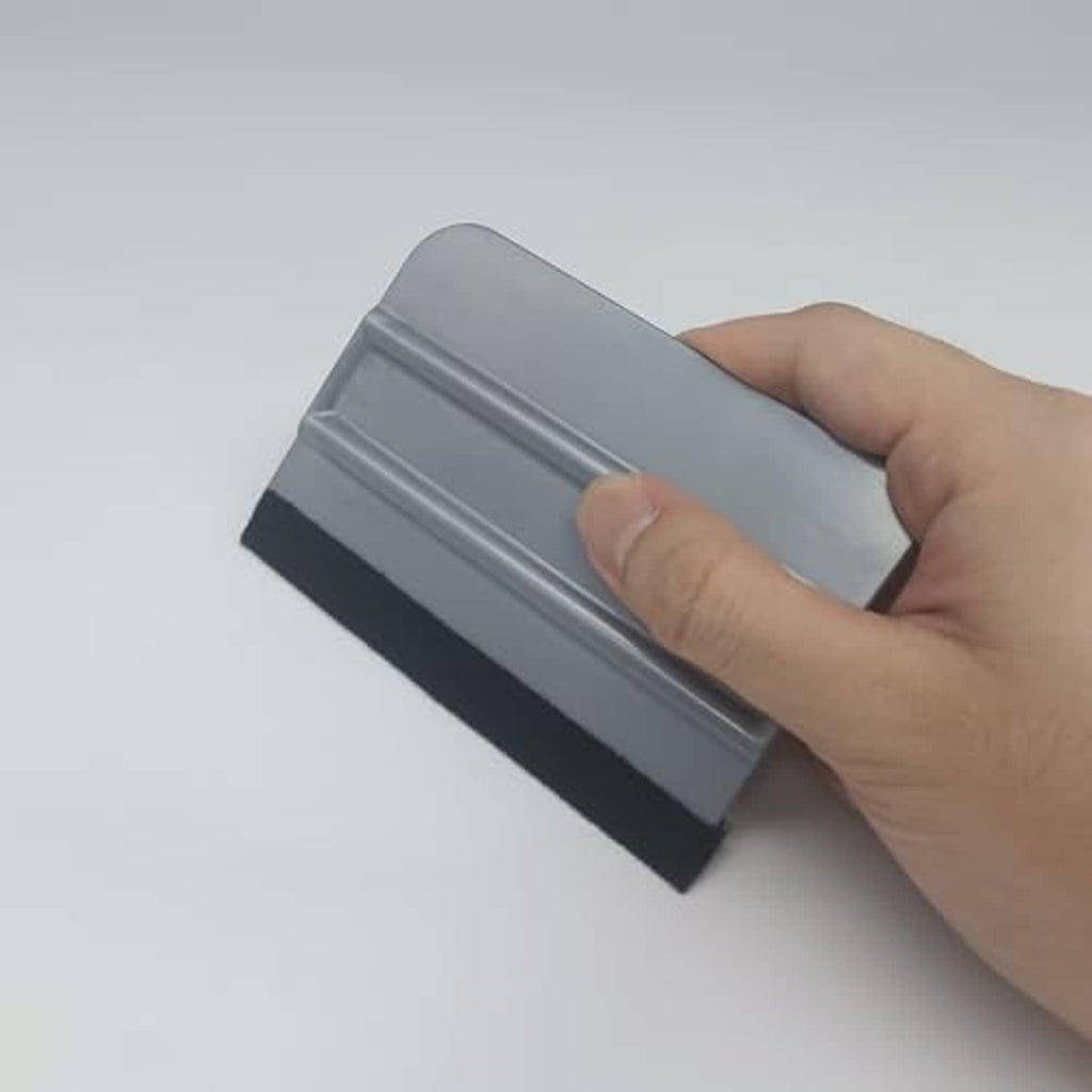 Vinyl wrap squeegee being pressed by hand, gray plastic with black felt edge
