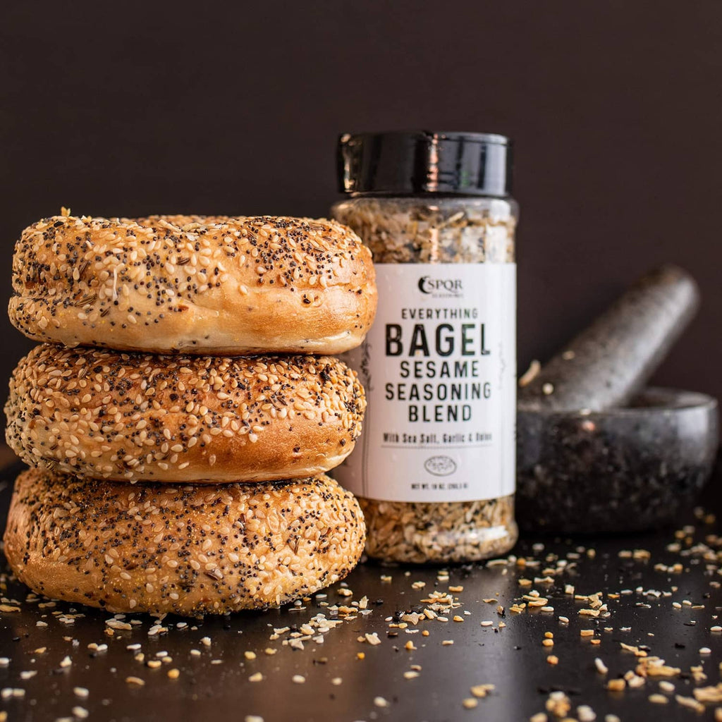 Everything bagel seasoning jar beside bagels with sesame and seasoning flakes