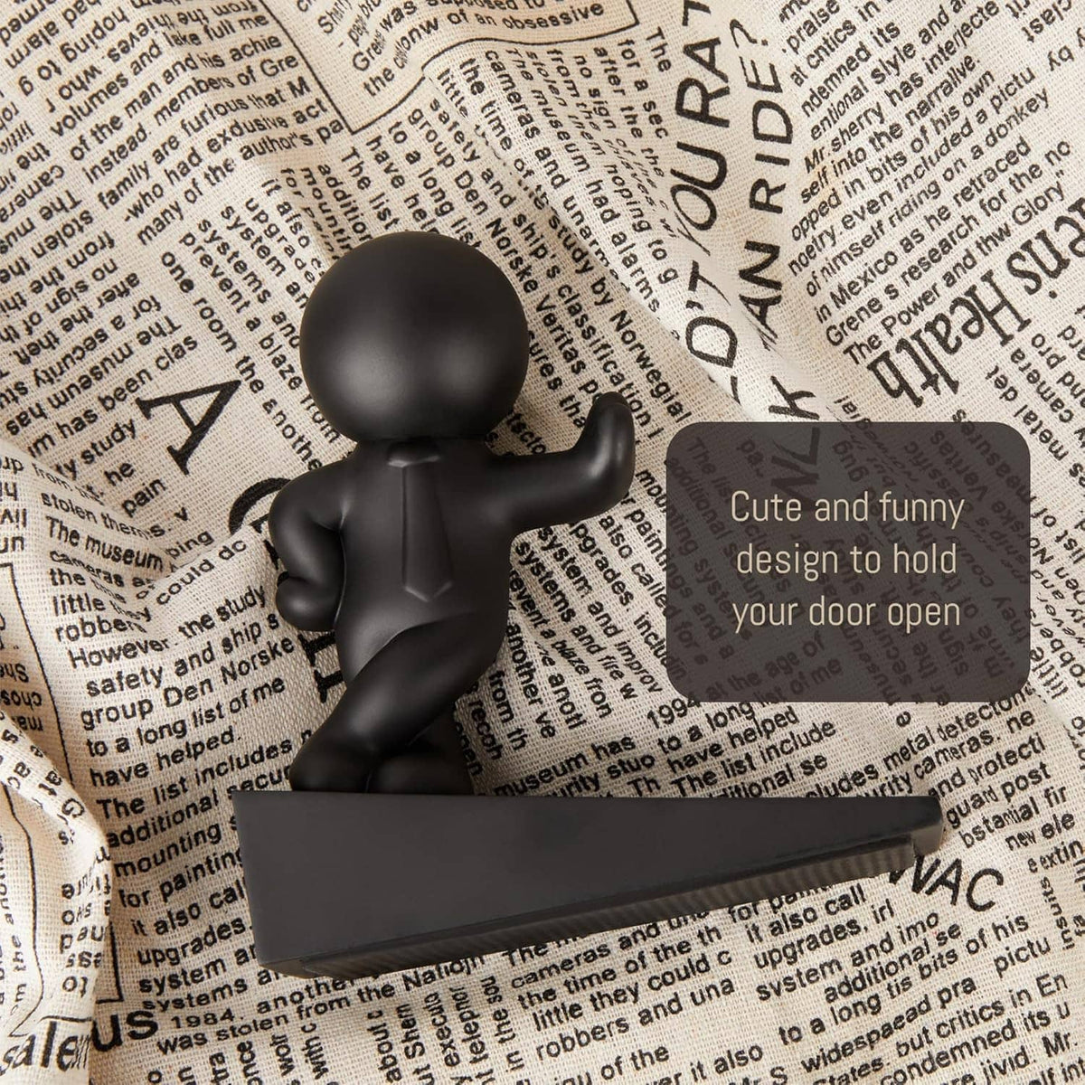 Black door stop figurine on a rectangular base, standing on printed text background.