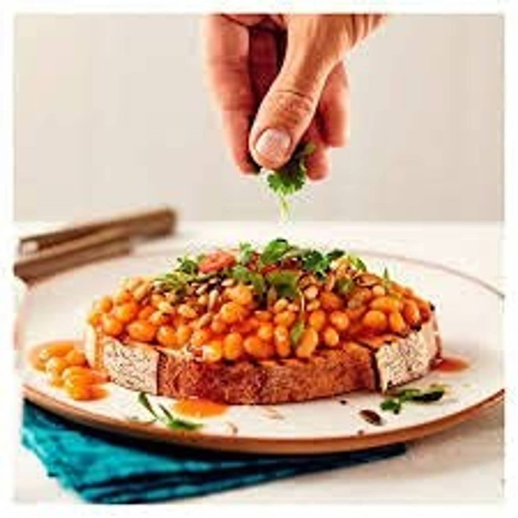 Heinz Beanz baked beans in rich tomato sauce on a plate with herbs