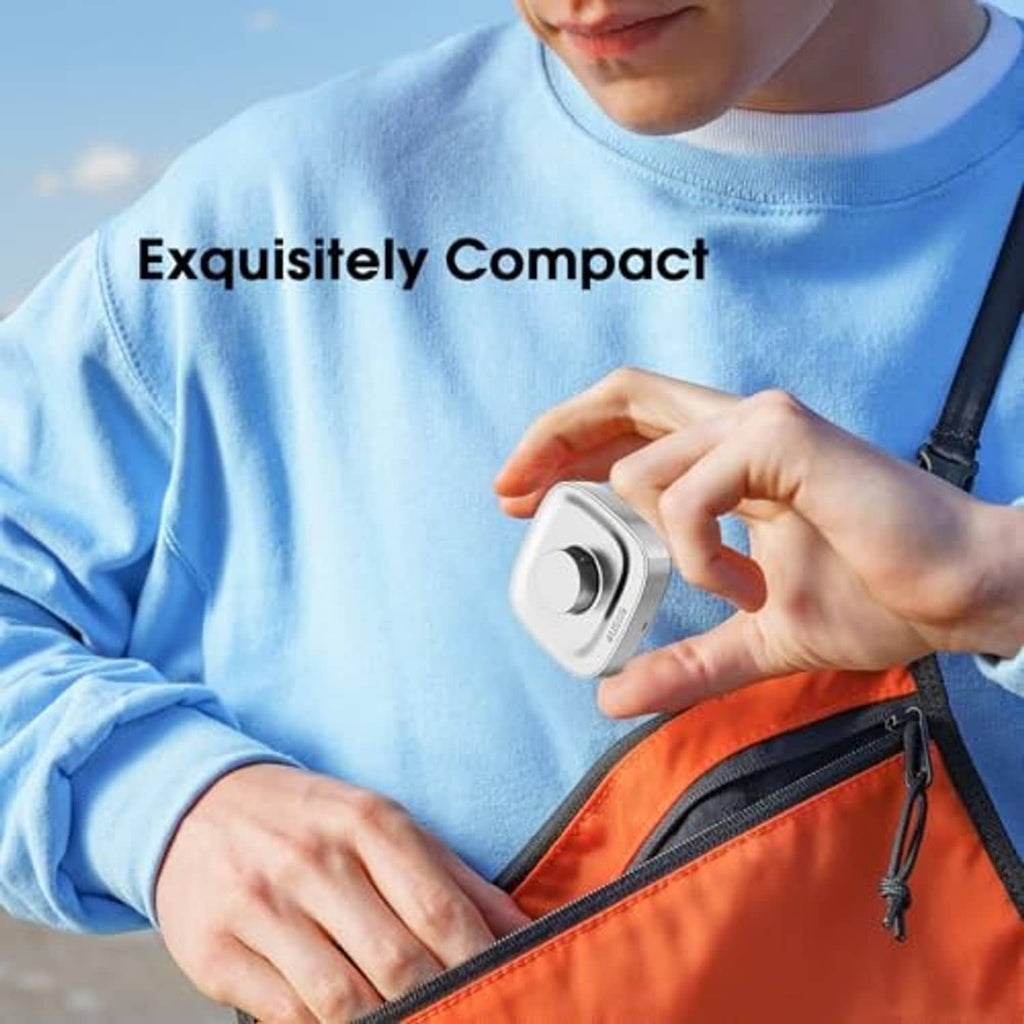 Compact Oura Ring Gen 4 charging dock, silver puck with blue indicator in hand