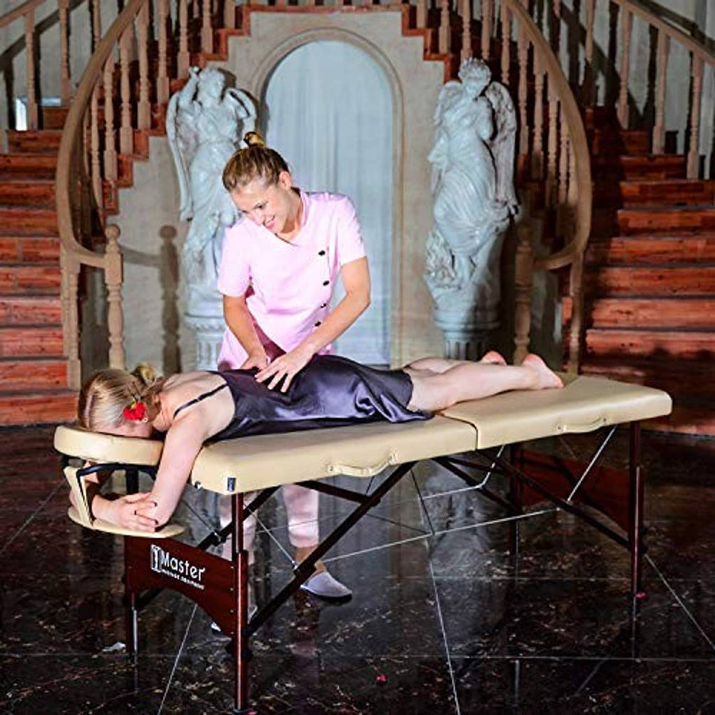 Portable massage table with cream upholstery and walnut frame, set for massage use