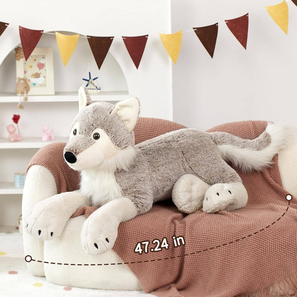 Large gray wolf plush stuffed animal on rust beanbag, white paws and tail visible