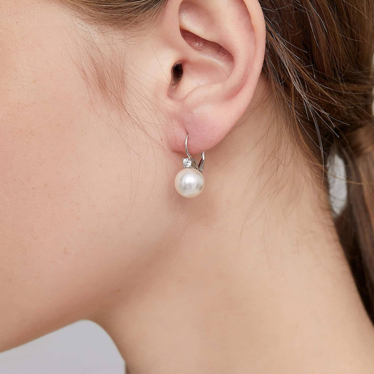 Sterling silver pearl leverback earrings shown in close-up: round white pearl and crystal detail