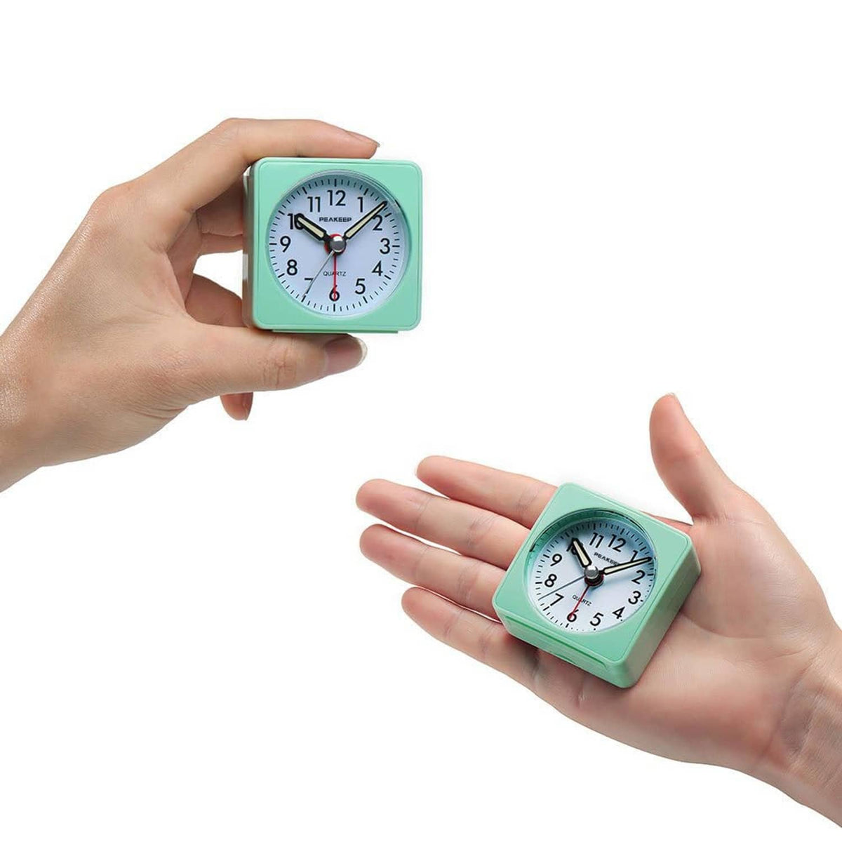 Mint teal mini travel alarm clock held in hands, quartz analog dial