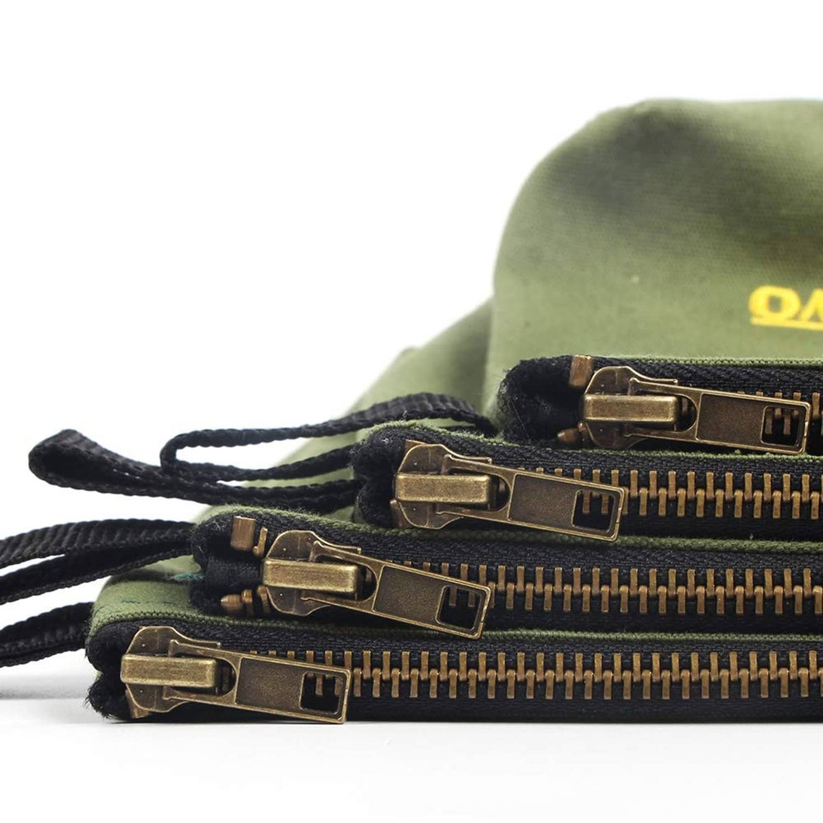 Olive canvas zipper pouch close-up with brass zipper and navy strap pull