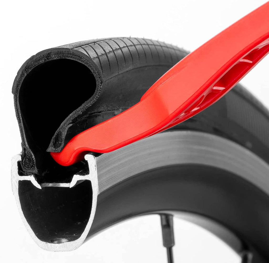Red tire lever with hook tip seated at tire rim and bead.