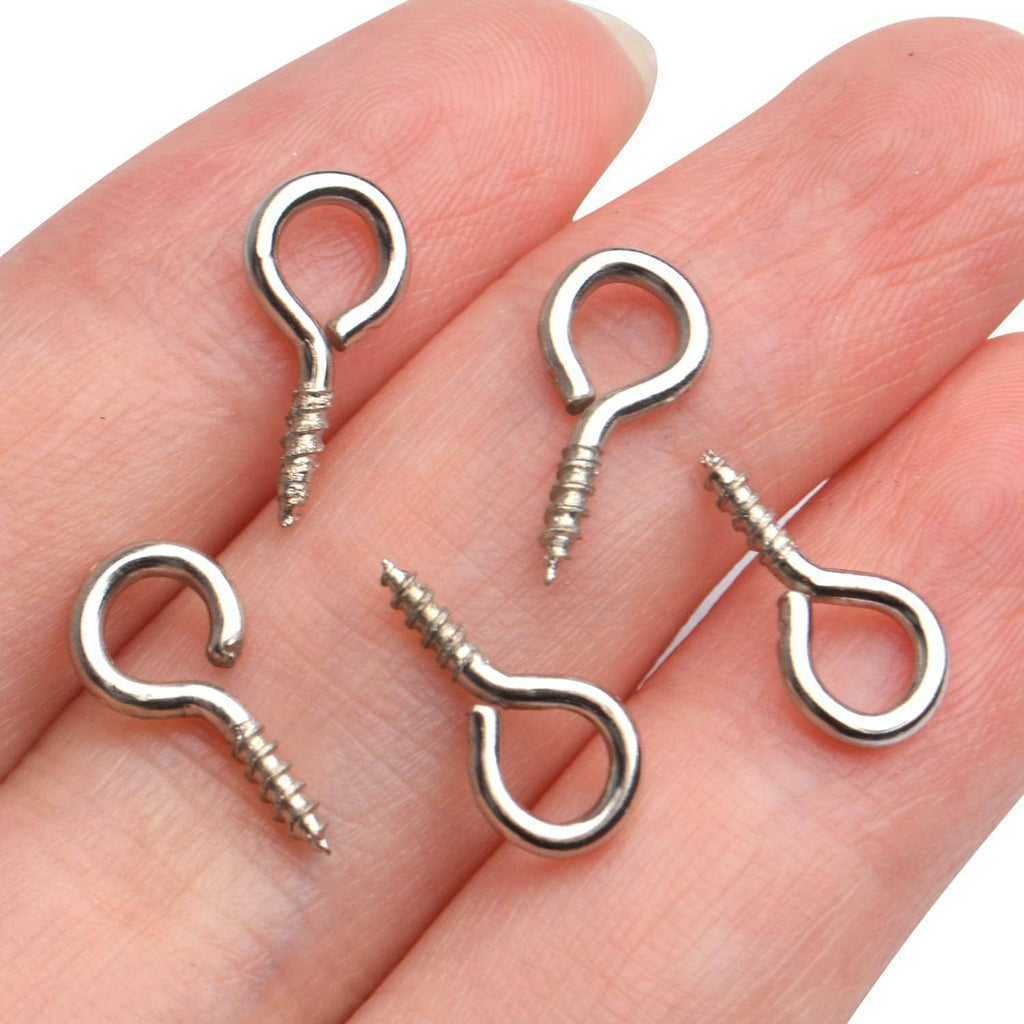 Assorted small silver eye screw hooks held in a hand, showing loop eyes and threads