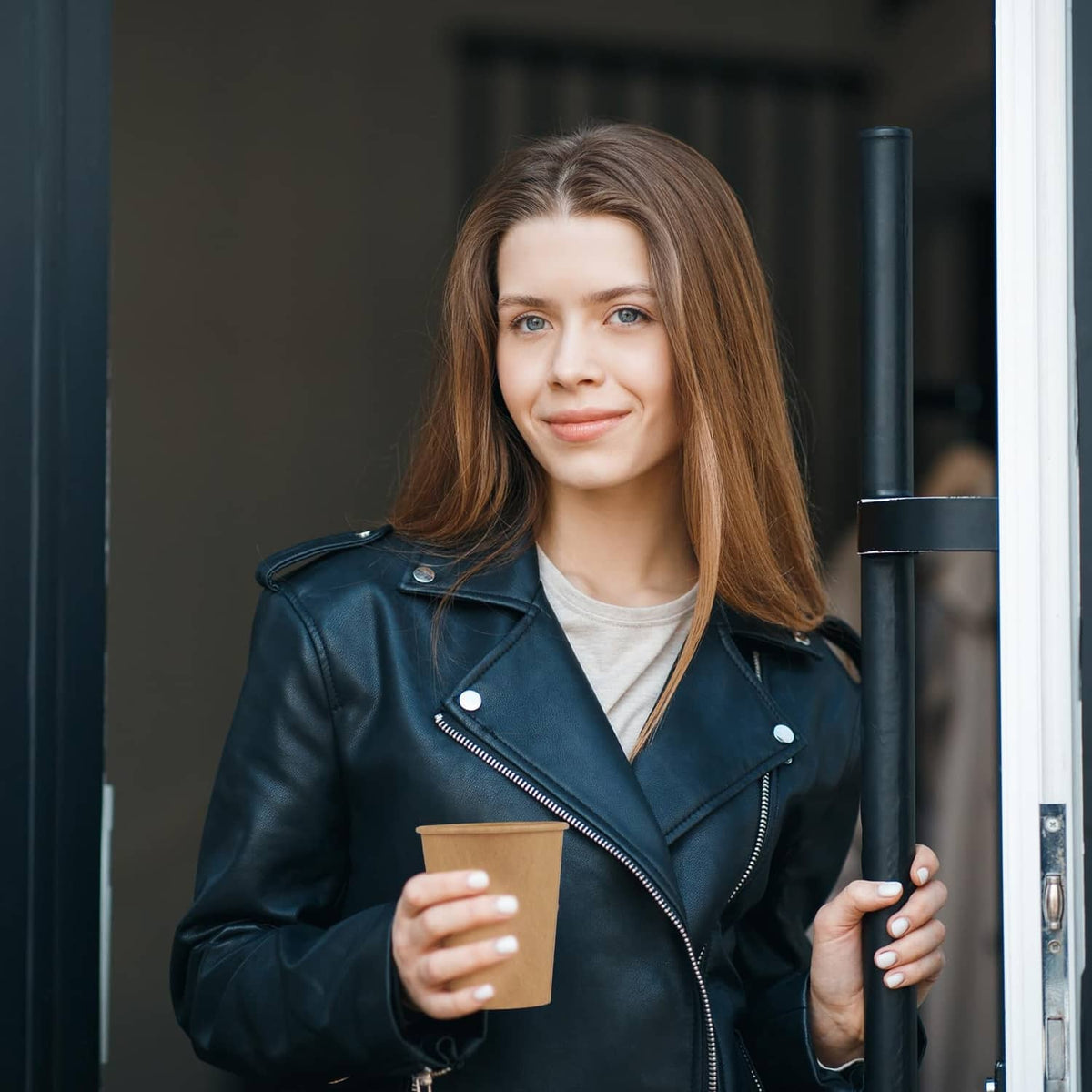 Brown kraft paper cup held in hand, upright disposable hot cup