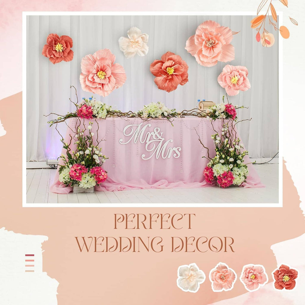 Wedding table decor with pastel coral and cream tissue paper flowers behind sign