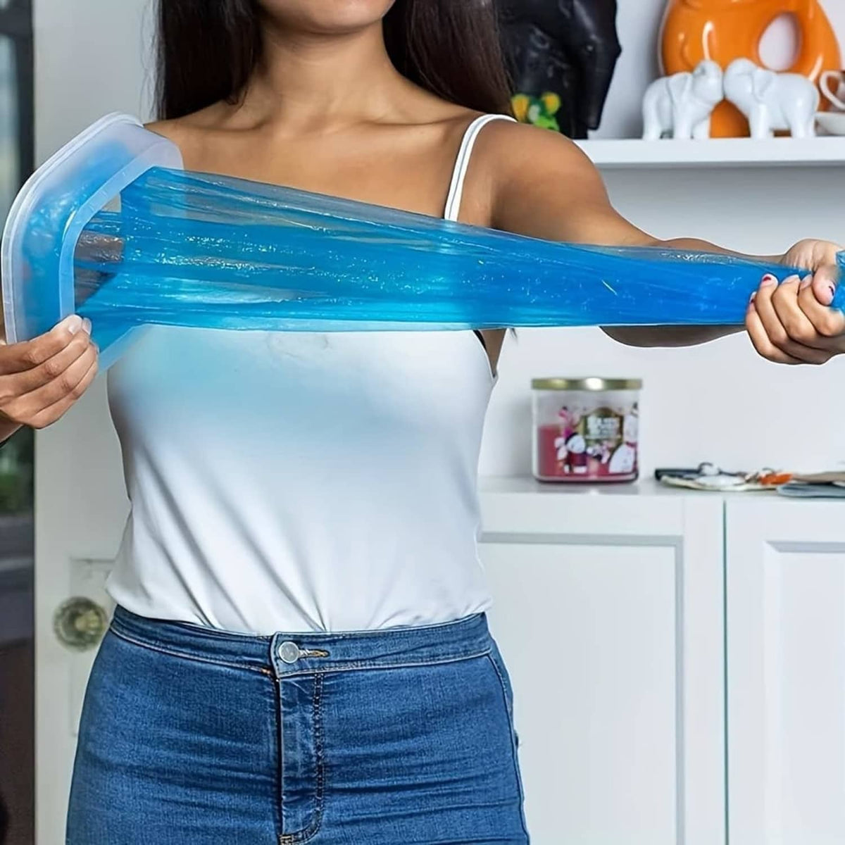 Person holding a long blue cat litter refill bag through the disposal system opening.