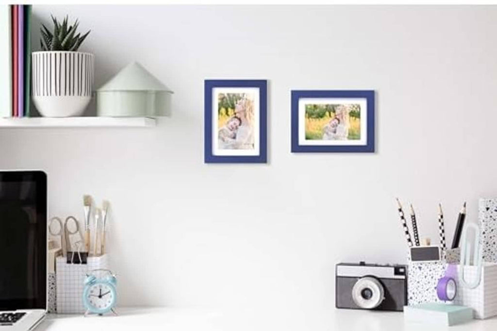 Two dark blue photo frames with landscape pictures on a wall