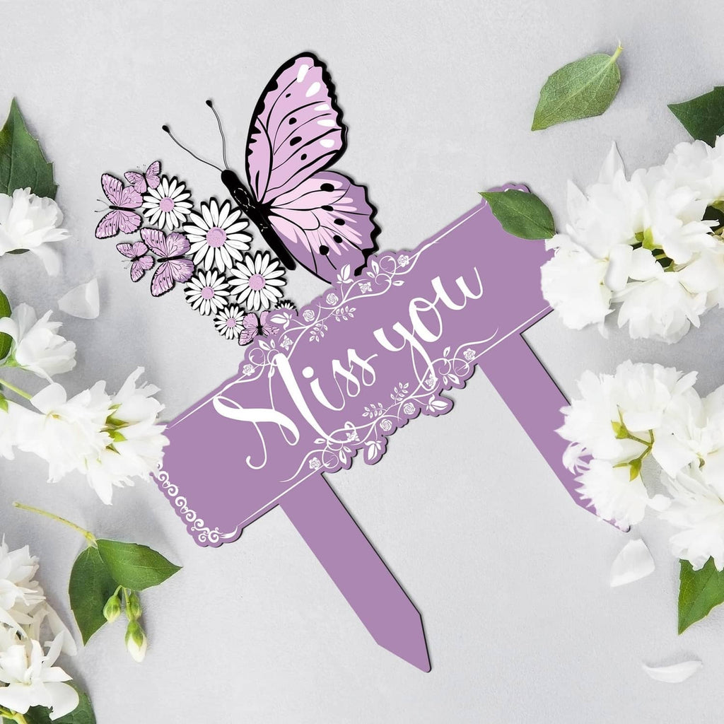 Purple memorial stake with 'Miss you' banner, butterfly, and white flower accents