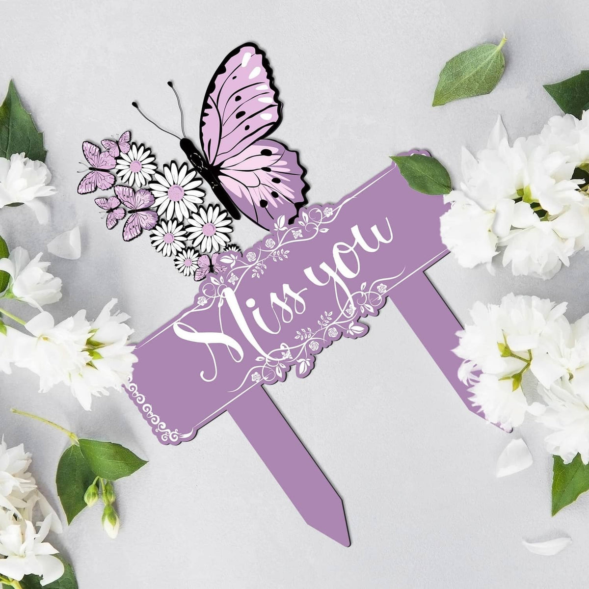 Purple memorial stake with 'Miss you' banner, butterfly, and white flower accents