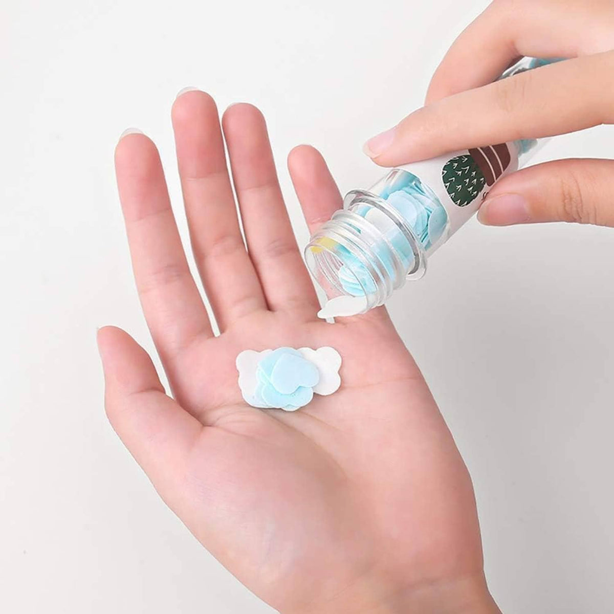 Portable soap confetti in small clear bottle, blue soap piece held in hand