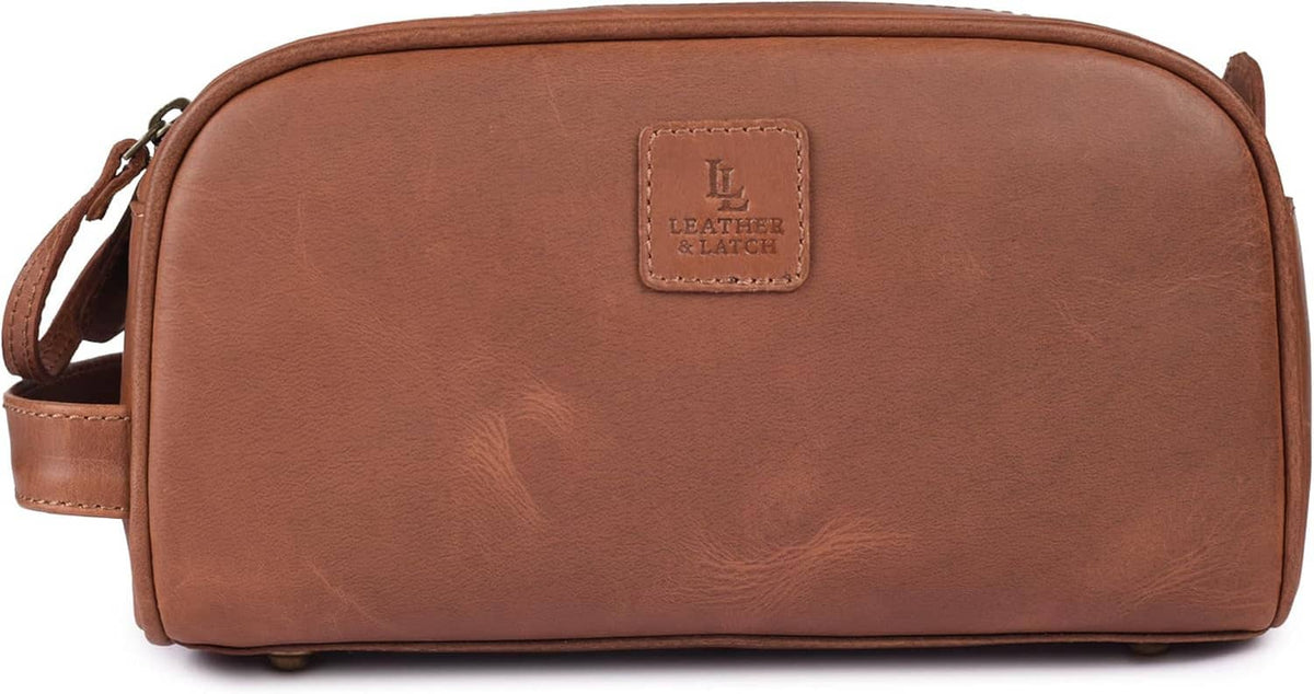 Brown leather toiletry bag with front logo patch and adjustable crossbody strap