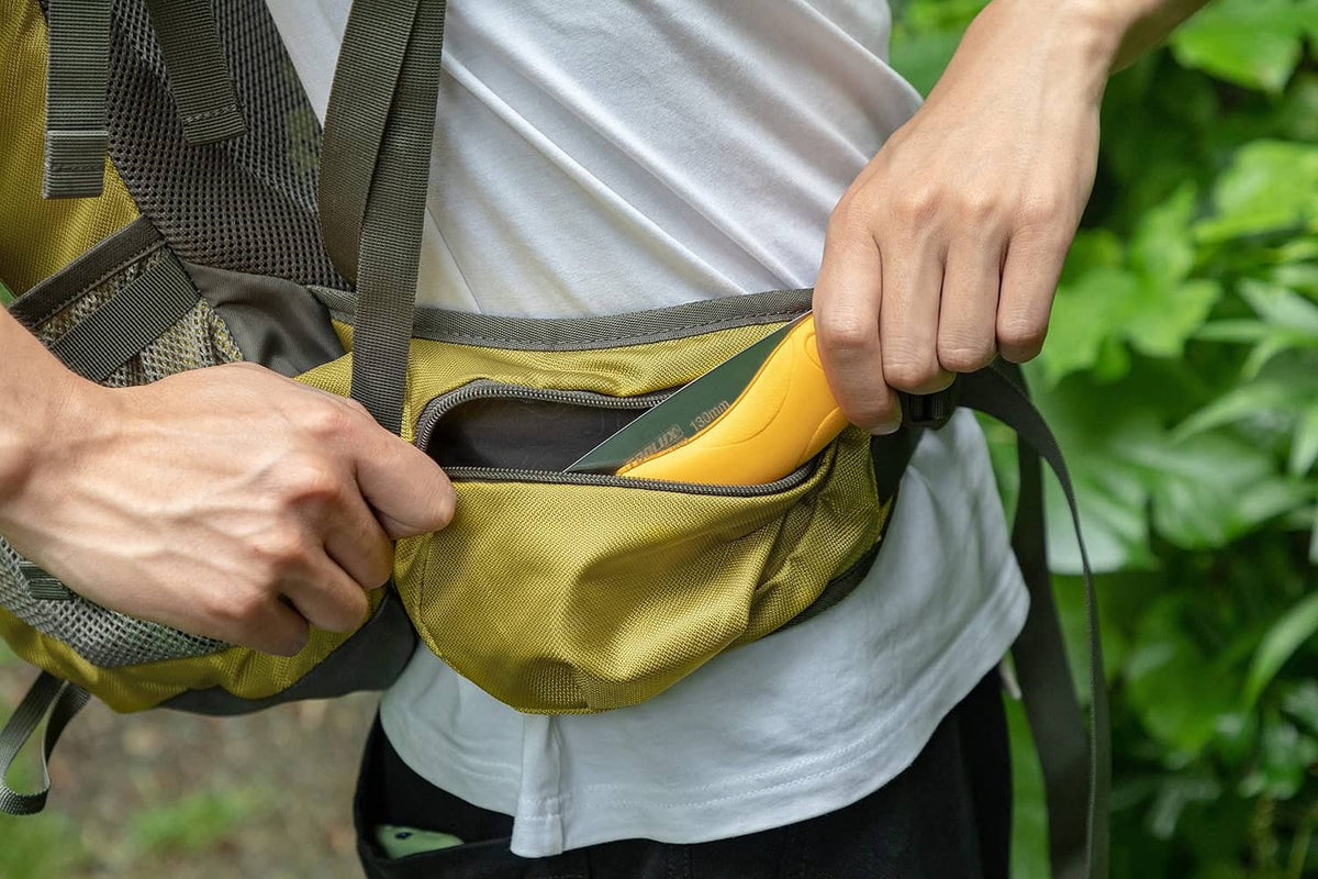 Folding pruning saw stored in a green bag pocket, yellow handle visible