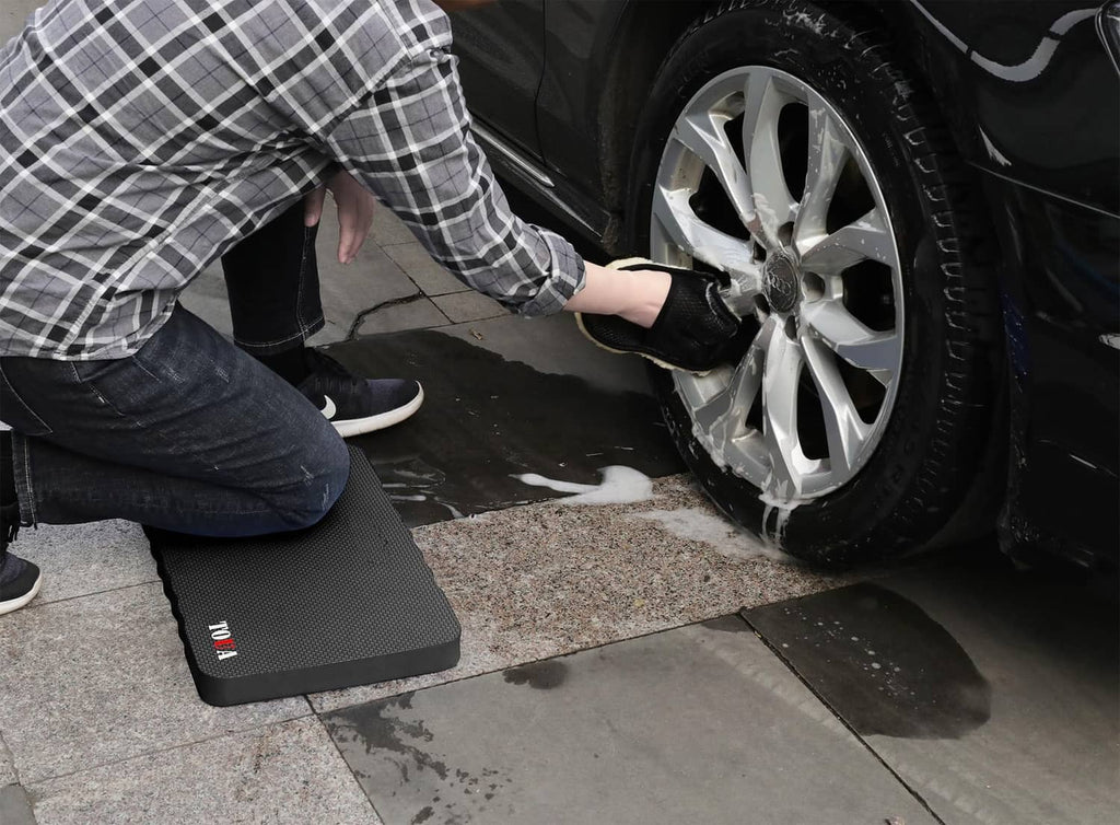 Large dark gray kneeling pad under a knee while working on a vehicle.
