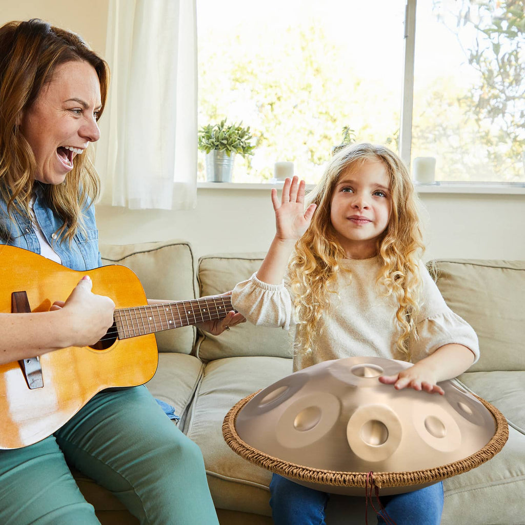 Handpan drum held on a seated child’s lap, golden tone surface with note dimples