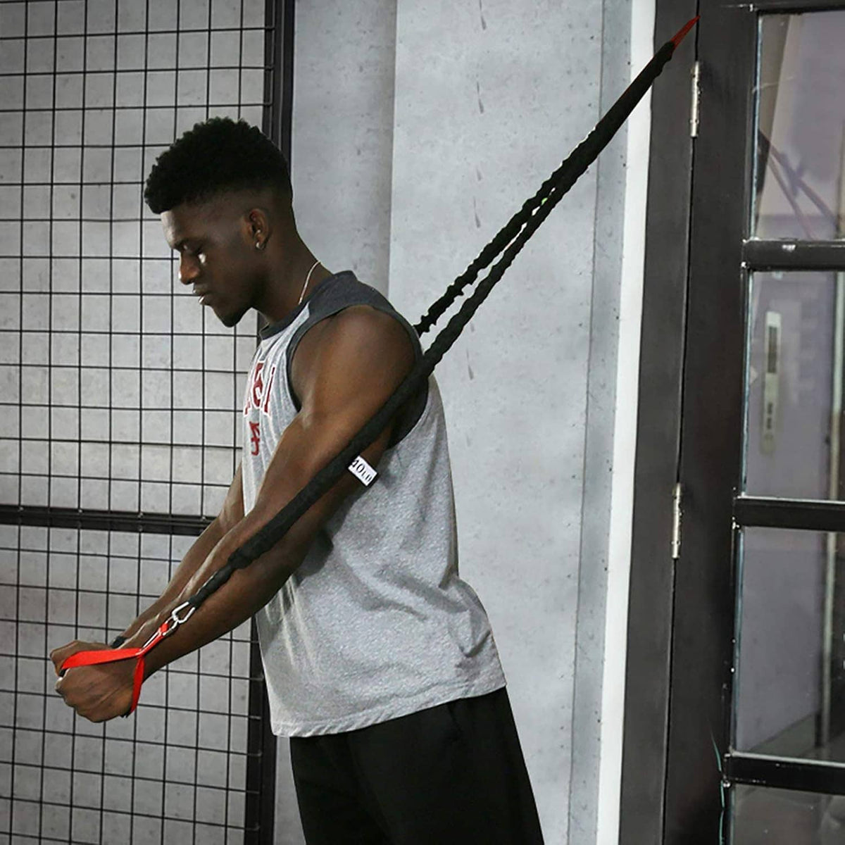 Black resistance band with red handle in use by a person in a gym