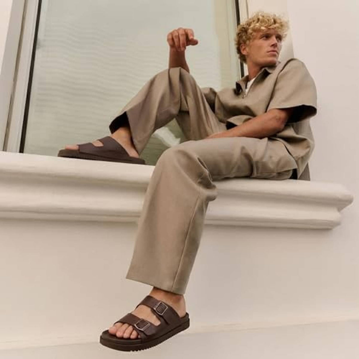 Men's brown adjustable buckle slide sandals worn with beige trousers