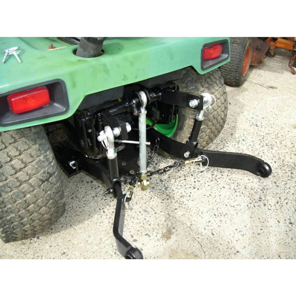 Rear 3-point hitch mounted on tractor with black arms, chains, and silver lift hardware