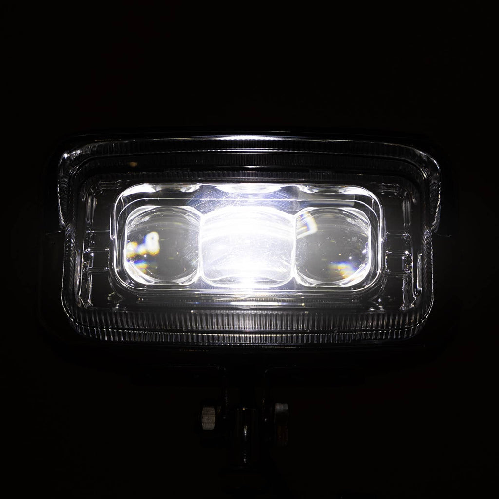 Rectangle front LED headlight glowing bright with clear lens and three internal emitters