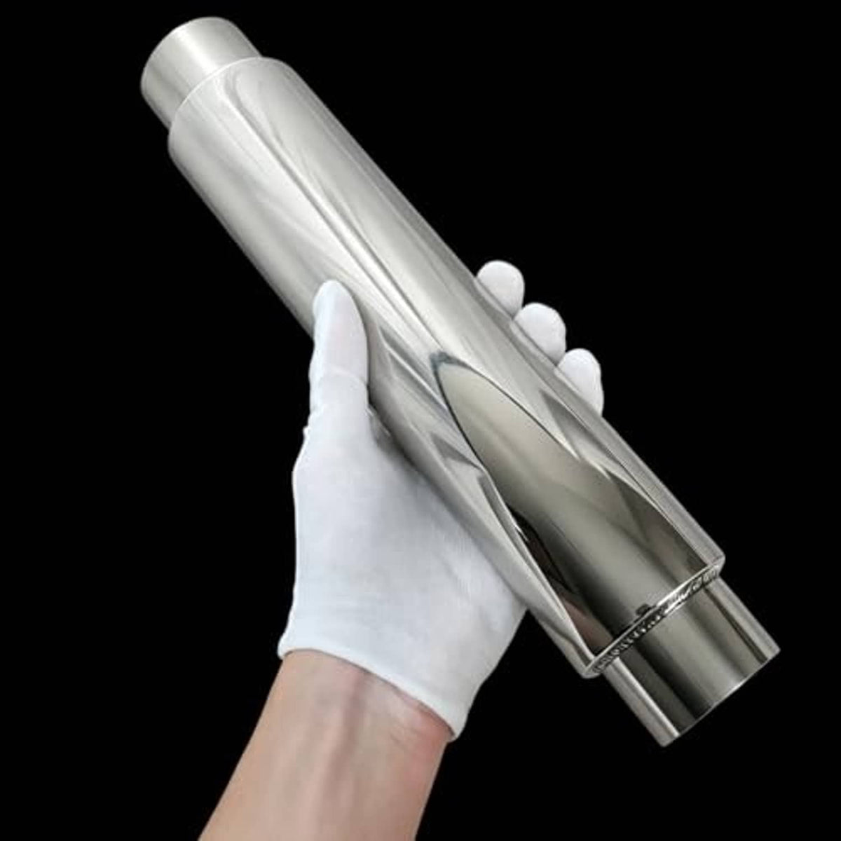 Stainless steel resonator muffler held in hand, showing cylindrical body and end opening
