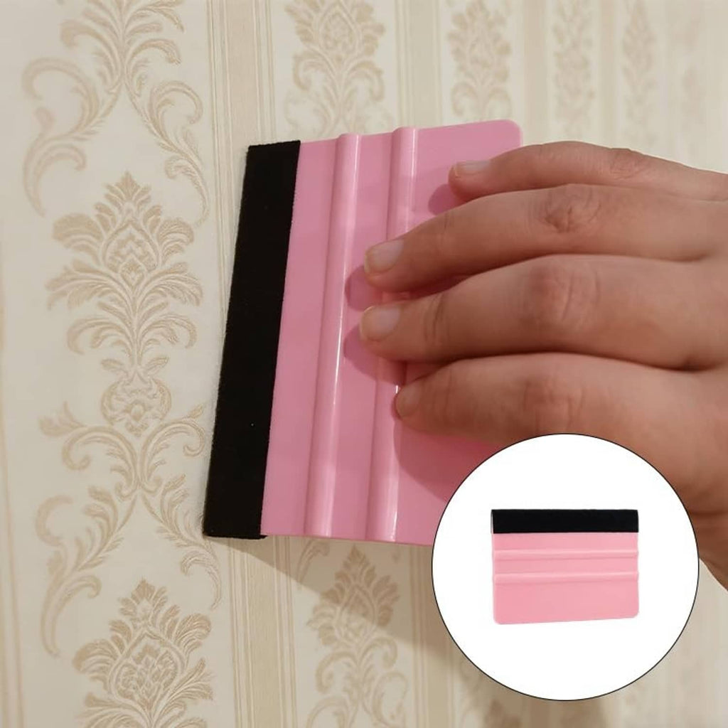 Hand pressing pink vinyl squeegee with black felt edge onto vinyl film