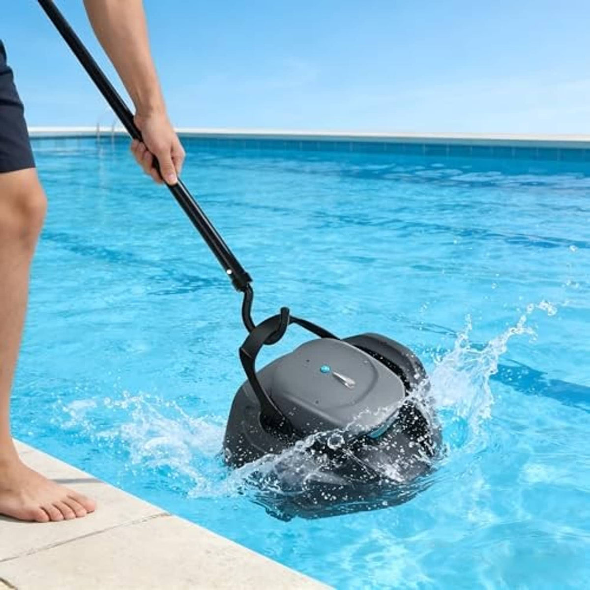 Black pool cleaner hook held by hand as water splashes around a robotic cleaner