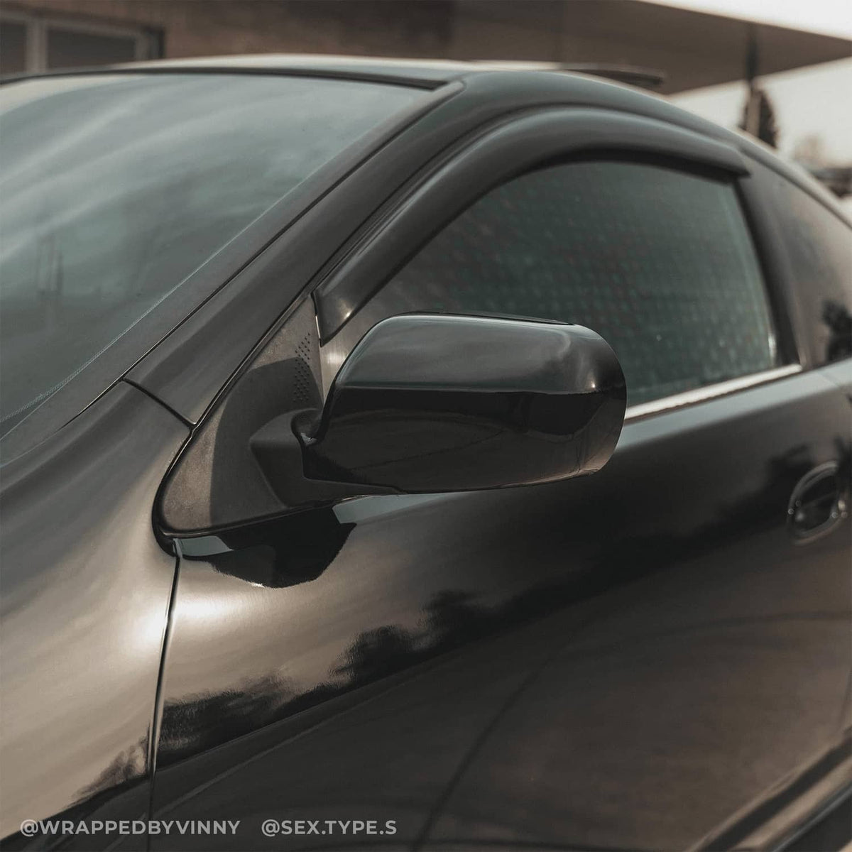 Black high-gloss vinyl-wrapped car door panel with side mirror, realistic paint-like finish