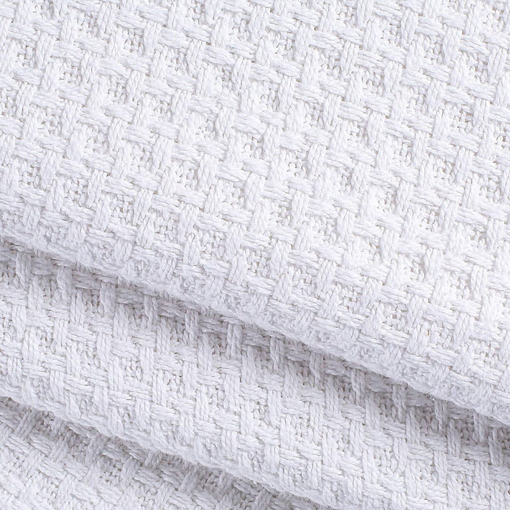 Close-up of white woven waffle-texture bed blanket fabric edge.