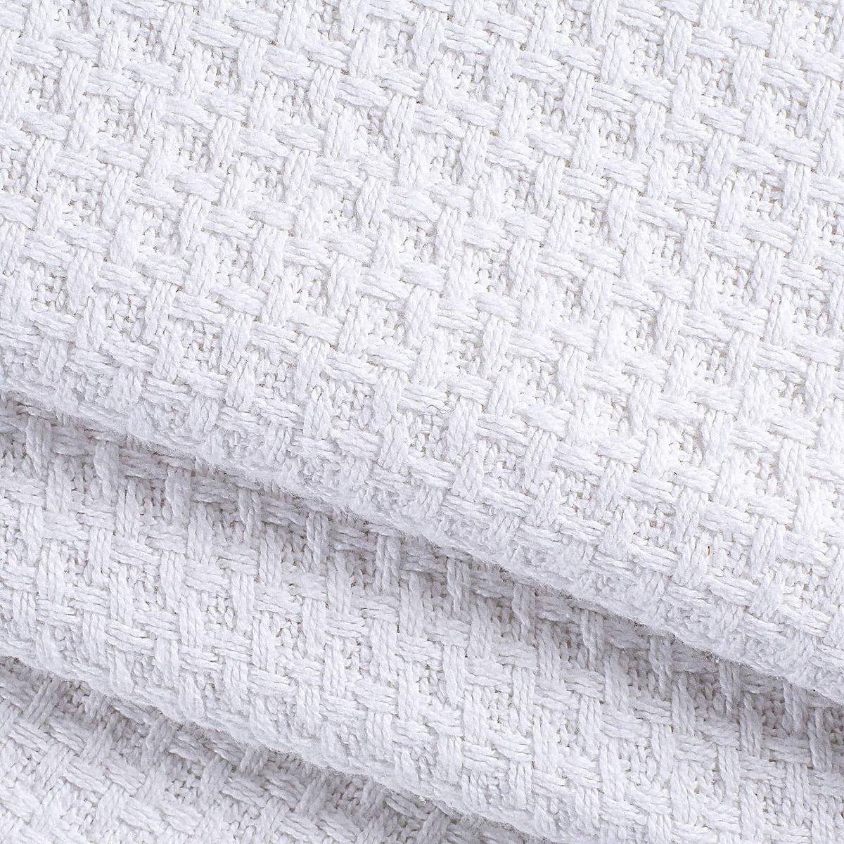 Close-up of white woven waffle-texture bed blanket fabric edge.