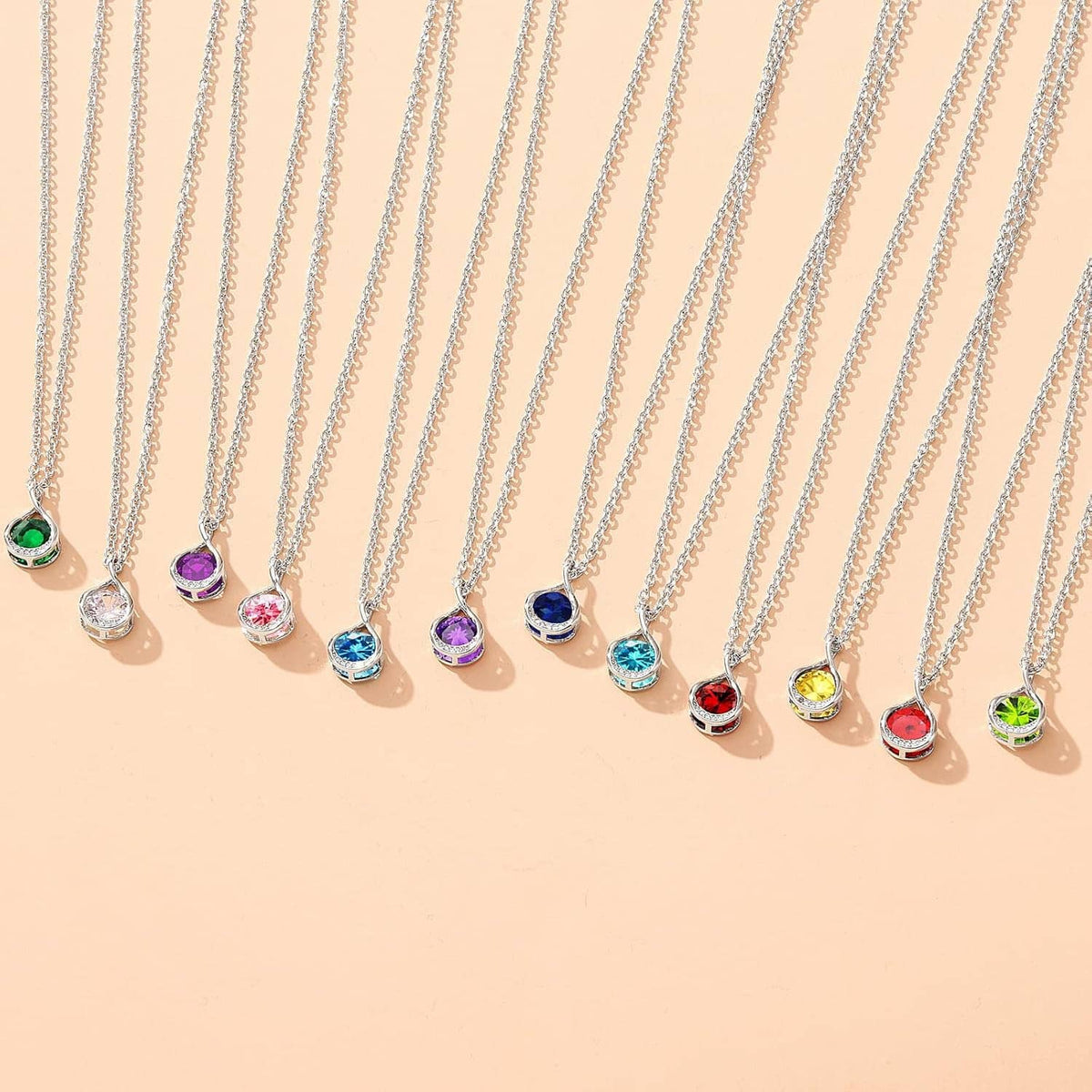 Row of silver birthstone-style charm necklaces with colorful teardrop pendants