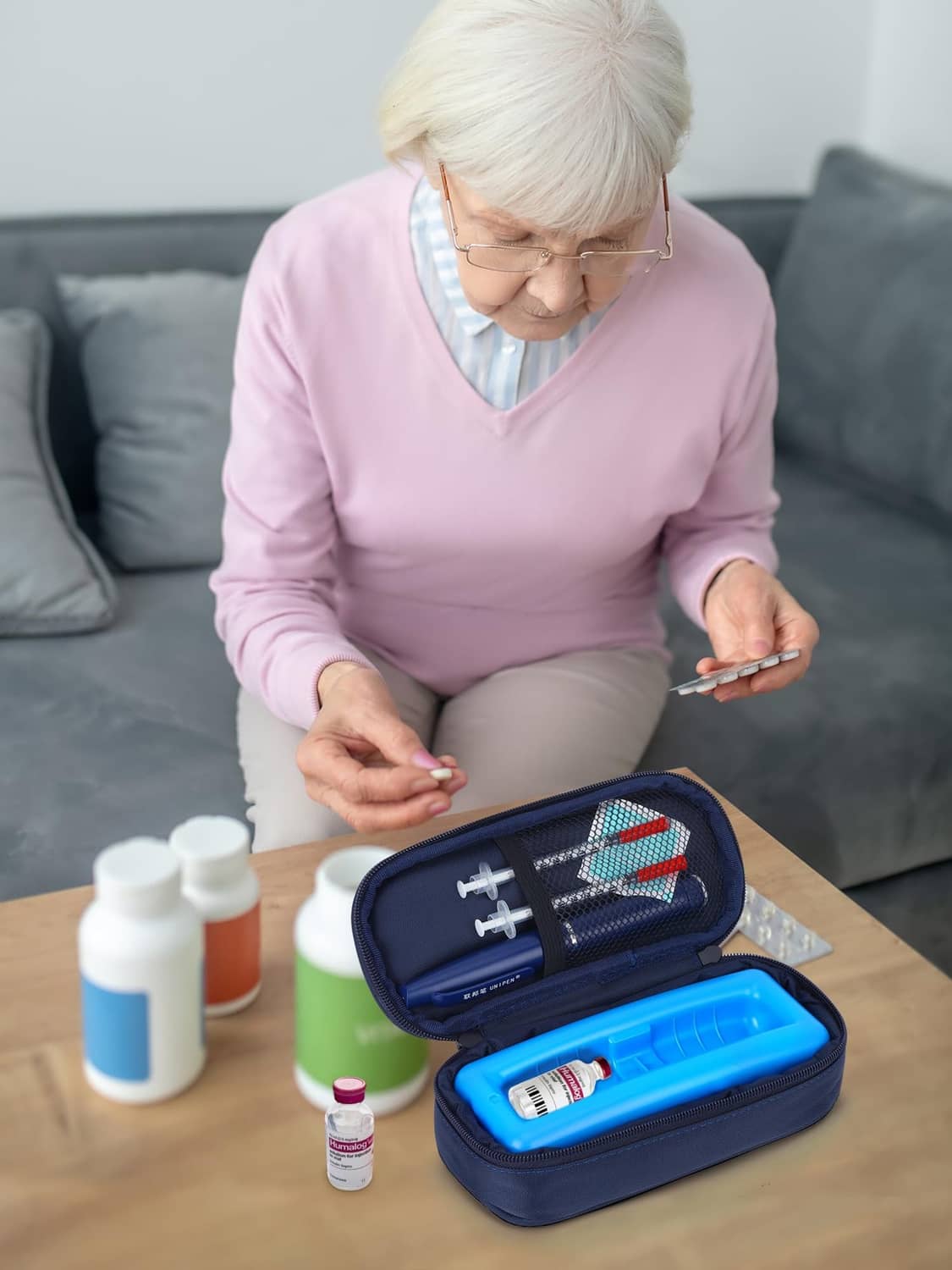 Insulin travel cooler case open on table beside syringes and vials, held during packing