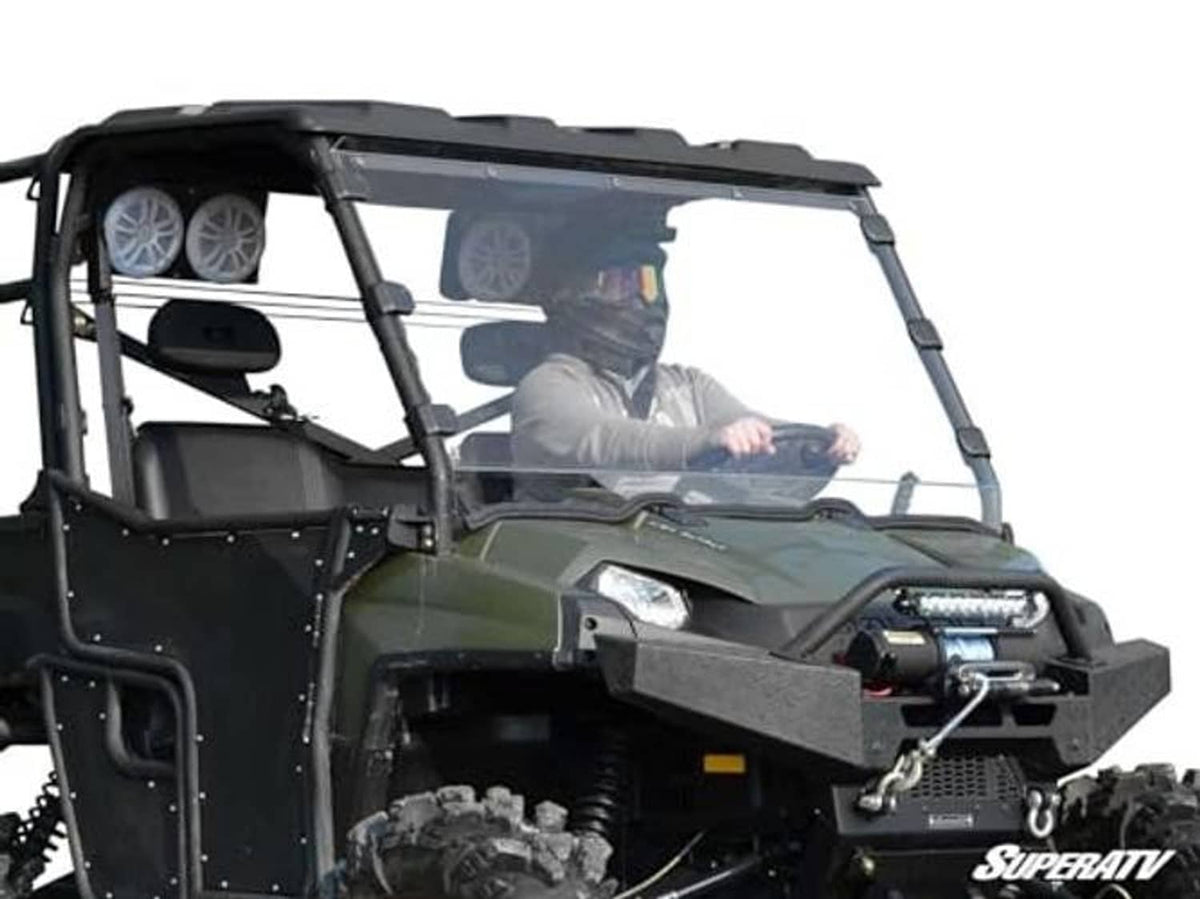 Front 3/4 view of clear full windshield installed on green UTV with driver visible