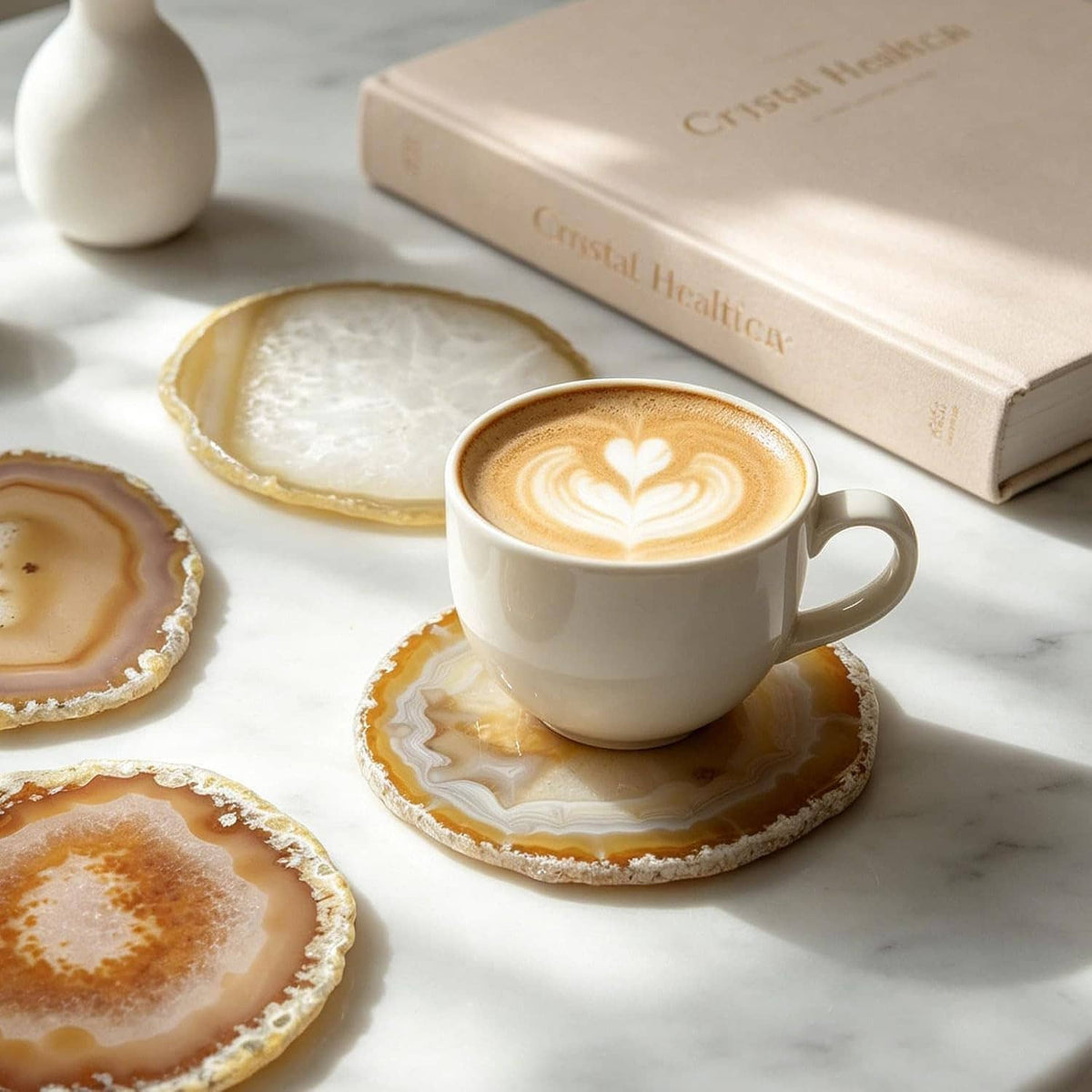 Agate geode coaster under a white coffee cup, with three matching coasters nearby