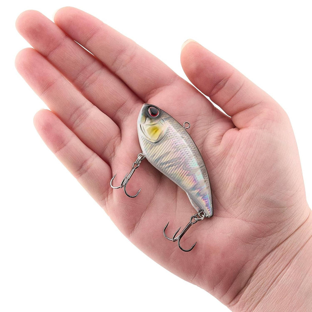 Silver fish-shaped lure with red eye and two treble hooks held in a hand