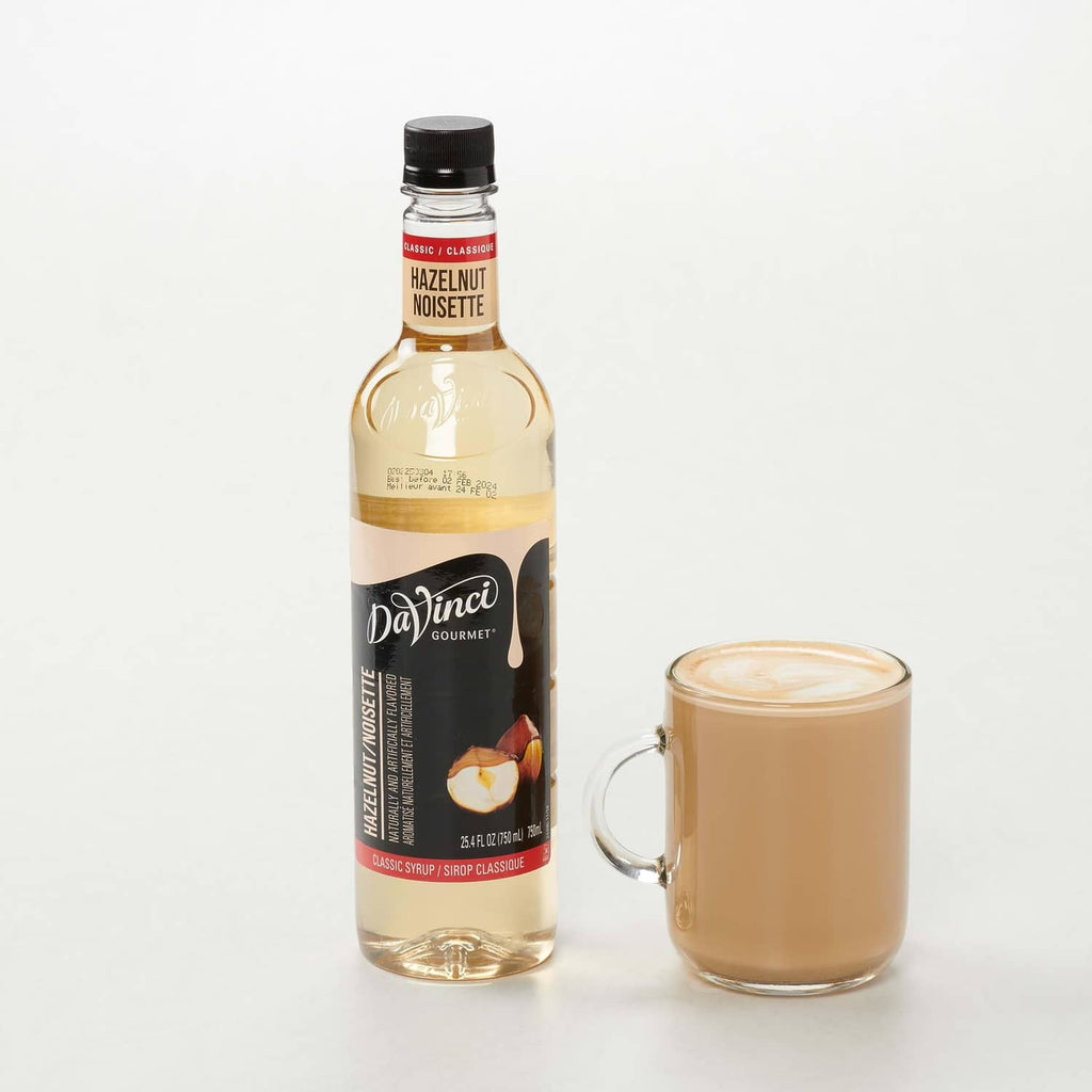 Hazelnut syrup bottle with black cap beside a glass jar of creamy latte drink