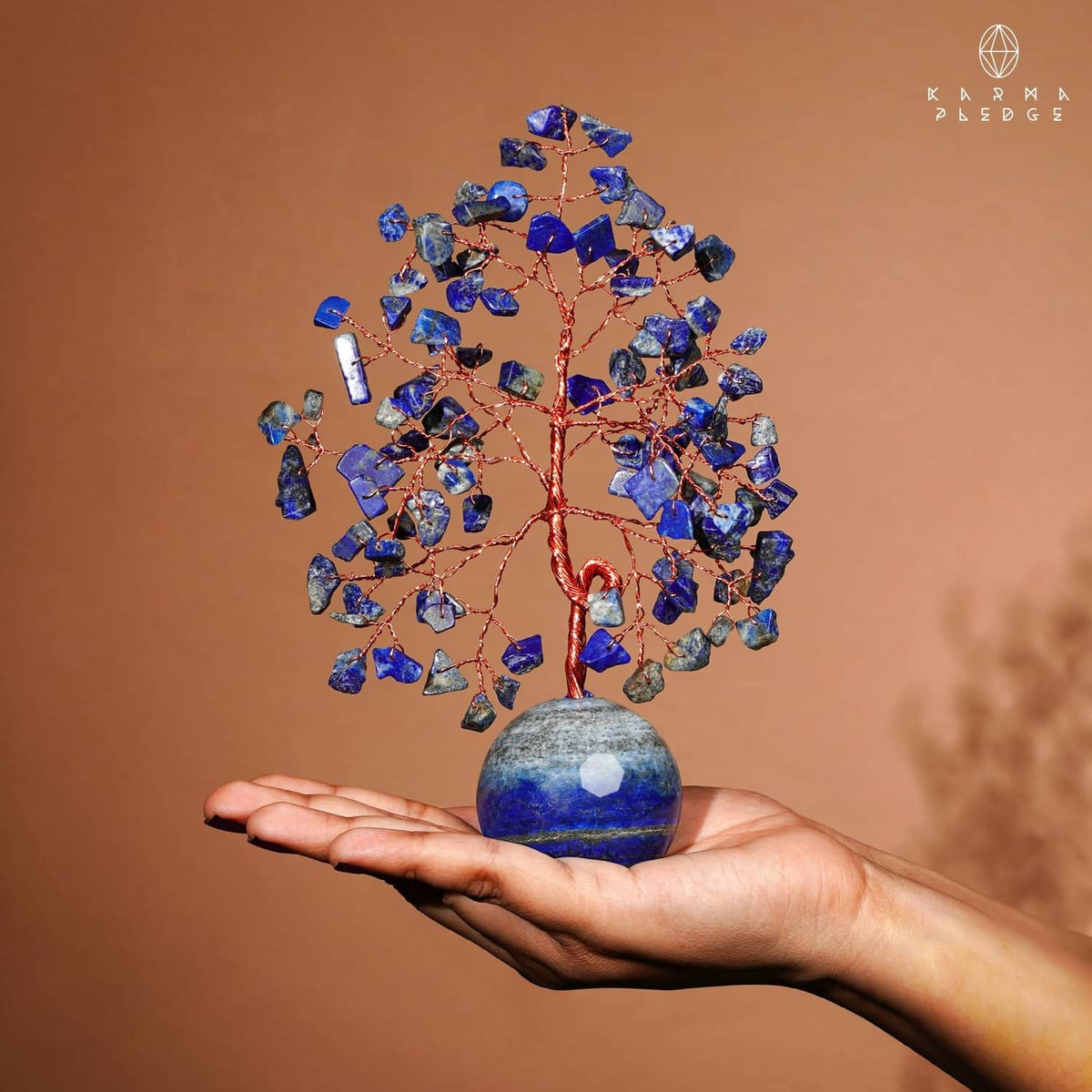 Tree of Life ornament of blue lapis lazuli stones with round base held in a hand