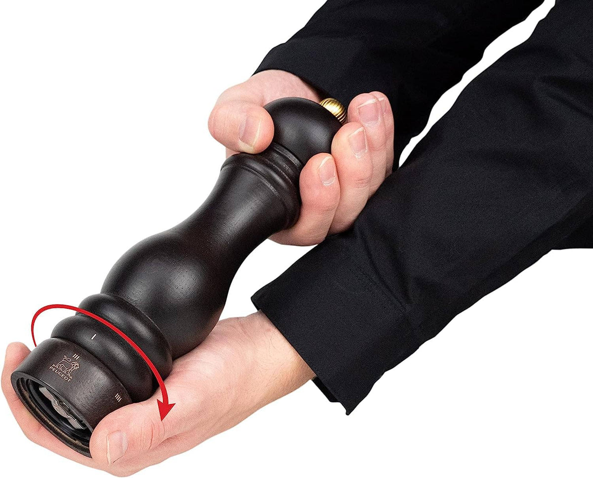 Wooden pepper mill in hand, showing bottom adjustment collar